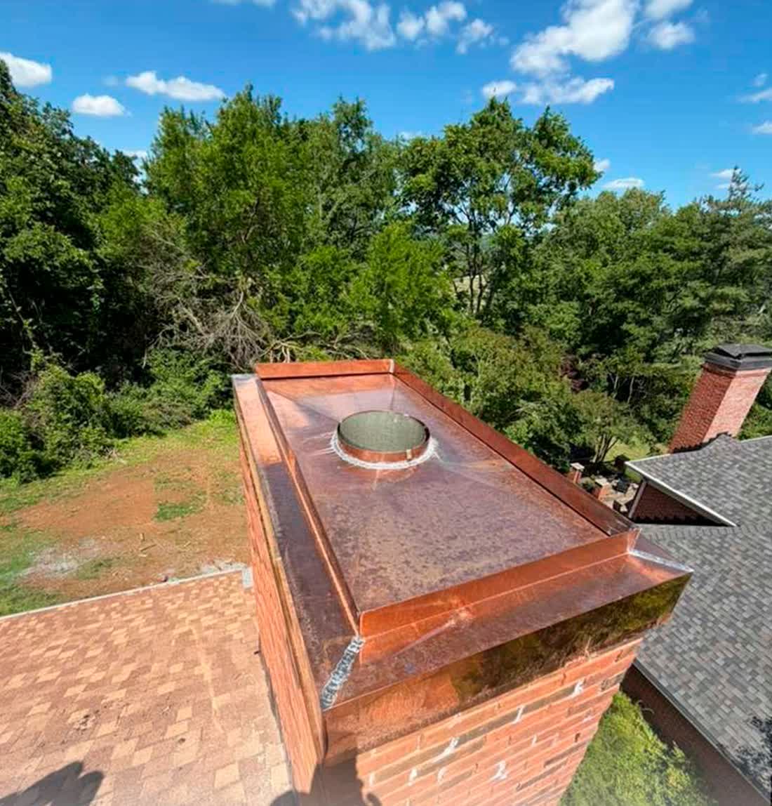 Three-piece copper chimney cap installed on a shingle roof