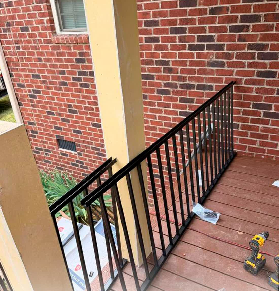 Finished deck with black metal railing against brick