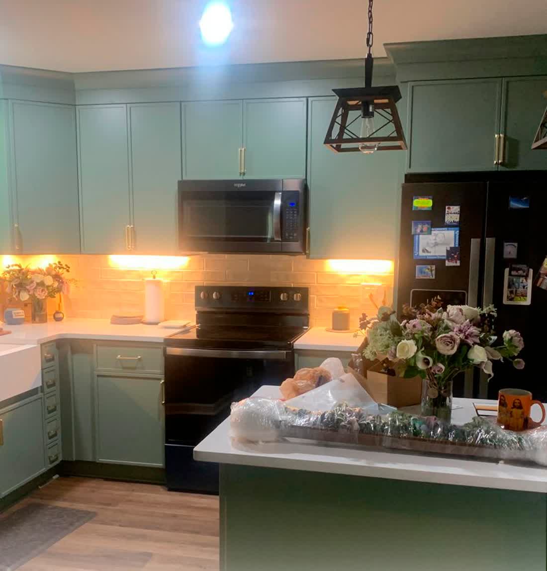 Renovated kitchen with green cabinets and stone countertops